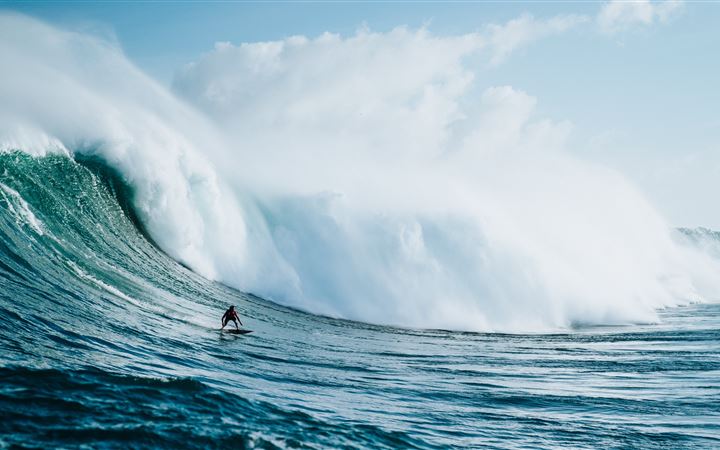 person riding on surfboard with waves behind iMac wallpaper