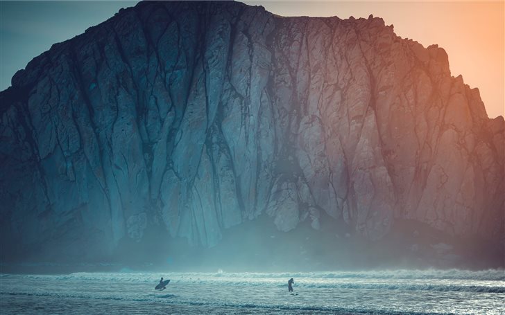 surfer on body of water near sea cliff during dayt Mac Wallpaper