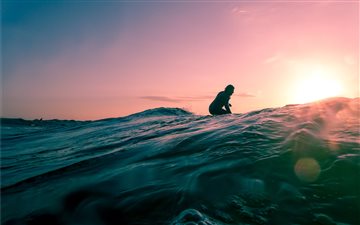 man surfing on ocean water during golden hour All Mac wallpaper