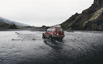 red SUV on water near mountain during daytime All Mac wallpaper